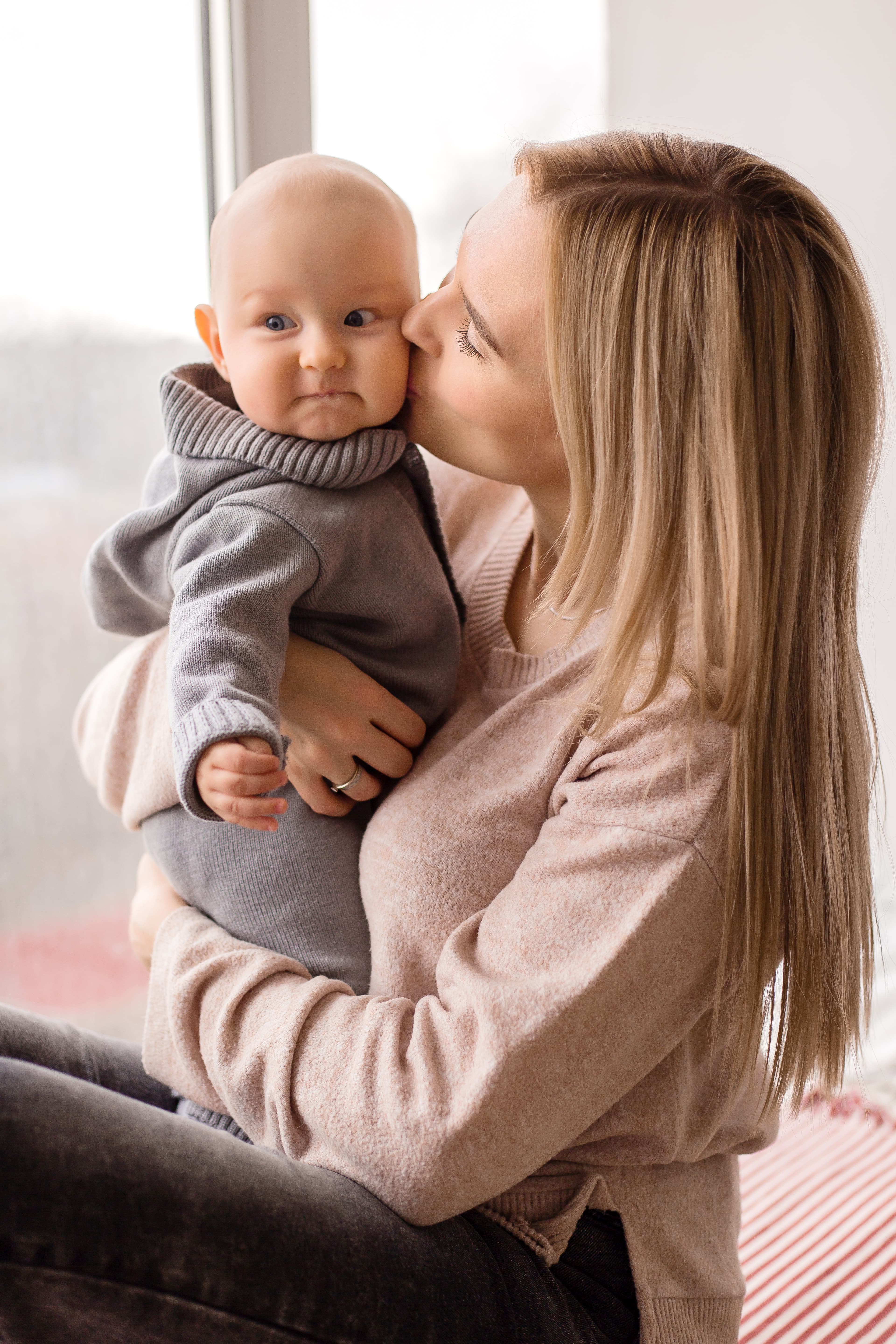 Loving Woman Holding Infant In Gray Outfit 2026 09 24 21 38 16 Utc